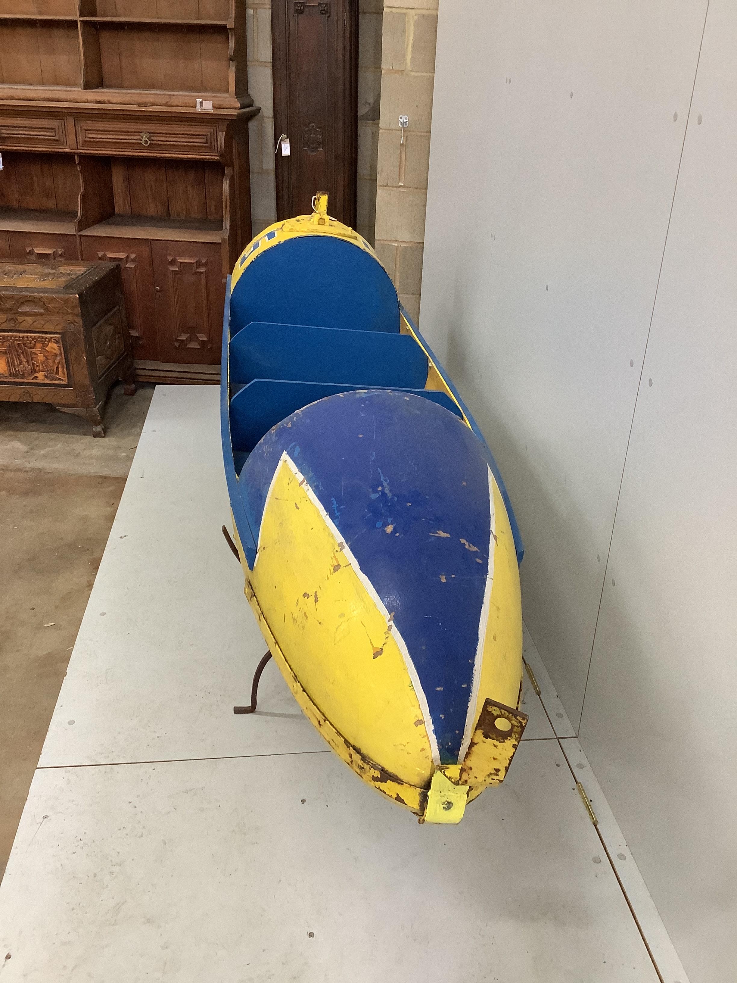 A vintage painted metal and wood torpedo shaped fairground ride seat, length 250cm, height 97cm